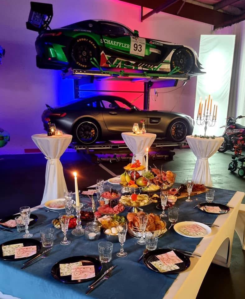 „Exklusive Eventlocation in Augsburg mit stilvoll gedecktem Tisch, moderner Beleuchtung und Sportwagen-Dekoration – ideal für Firmenfeiern und Produktpräsentationen.“